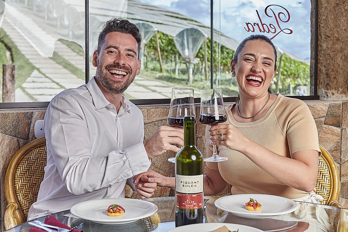 Casal brindando com vinho no restaurante da vinícola